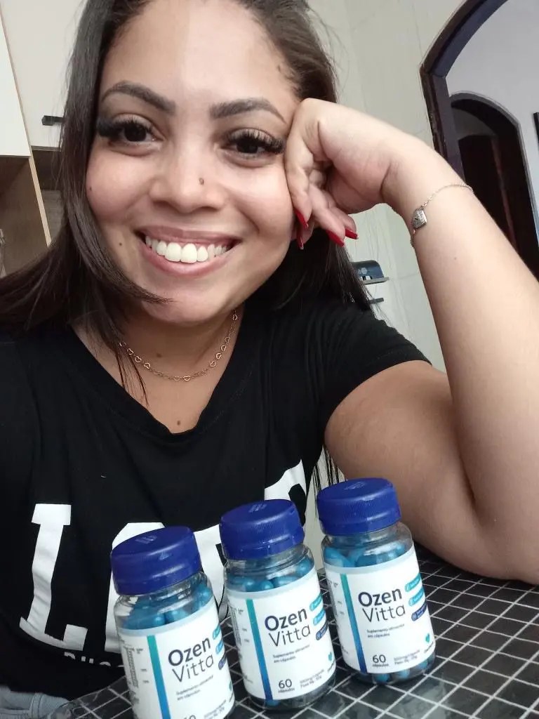 Mulher sorridente segura o frasco de Ozenvitta, destacando confiança no suplemento natural para emagrecimento saudável.

